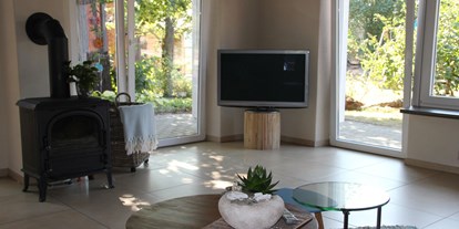 Monteurwohnung - Lingen - Fernseher und Kamin im geräumigen Wohnzimmer mit Blick in den Garten - Ferienhaus "NaturPur"