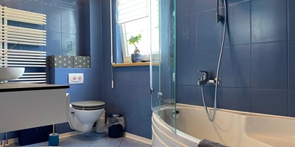Monteurwohnung - WLAN - Naunhof - Badezimmer Obergeschoss mit Badewanne und Duschhalterung mit Glasspritzschutz, Toilette und Waschtisch - Kerstin Schilling