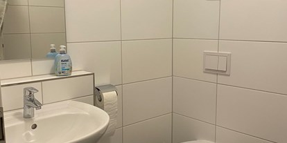 Monteurwohnung - Bettwäsche: Bettwäsche inklusive - Ofterdingen - Bad mit Toilette und Dusche links vom Bild.  - Monteurzimmer Spatz