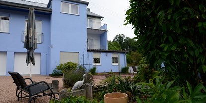 Monteurwohnung - Waschmaschine - Waldmohr - Rückansicht mit Relaxbank am Koiteich - Family Lodge Birkenhof & Biergarten