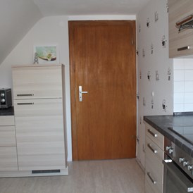 Monteurzimmer: andere Seite der Küche mit Kühl- Gefrierkombination und Microwelle - Ferienwohnung-Fulda