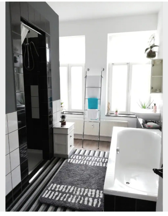 Monteurwohnung - Küche: Küchenmitbenutzung - Bathroom with two showers, two sinks, and a bathtub. - Sunrise Apartment