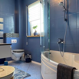 Monteurzimmer: Badezimmer Obergeschoss mit Badewanne und Duschhalterung mit Glasspritzschutz, Toilette und Waschtisch - Kerstin Schilling