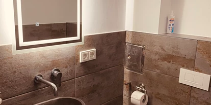 Monteurwohnung - PLZ 35781 (Deutschland) - Waschbereich mit beleuchtetem Spiegel und Naturstein Waschbecken  - Sweet Lounge