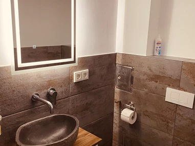 Monteurzimmer: Waschbereich mit beleuchtetem Spiegel und Naturstein Waschbecken  - Sweet Lounge