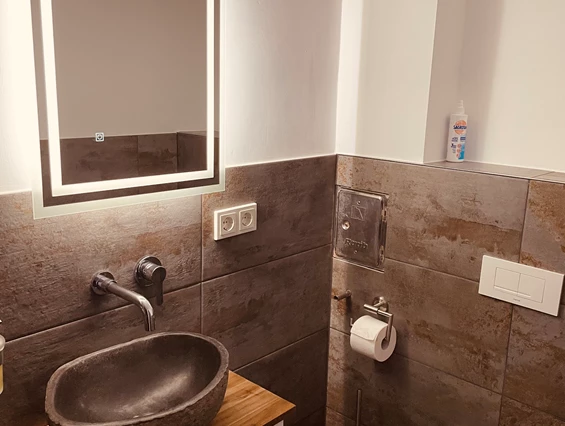 Monteurzimmer: Waschbereich mit beleuchtetem Spiegel und Naturstein Waschbecken  - Sweet Lounge