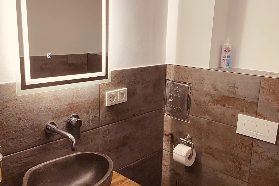 Monteurzimmer: Waschbereich mit beleuchtetem Spiegel und Naturstein Waschbecken  - Sweet Lounge