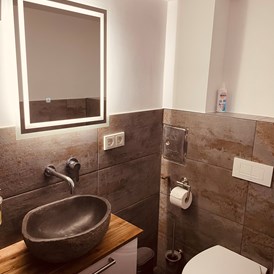 Monteurzimmer: Waschbereich mit beleuchtetem Spiegel und Naturstein Waschbecken  - sweet Lounge WIFI, Parklplatz Netflix, Garten 