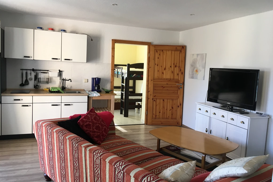 Monteurzimmer: Küchenzeile und im Hintergrund ein Raum mit Hochbett und Liege -davon ab geht es zum Badezimmer mit Dusche , WC und Waschbecken - Ferienwohnung Seeblick