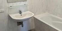 Monteurwohnung - Kühlschrank - Süd & West Steiermark - Badezimmer mit Waschbecken und Badewanne in der Monteurunterkunft in Dobl-Zwaring. - Azra Sinanovic
