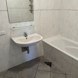 Monteurzimmer: Badezimmer mit Waschbecken und Badewanne in der Monteurunterkunft in Dobl-Zwaring. - Azra Sinanovic
