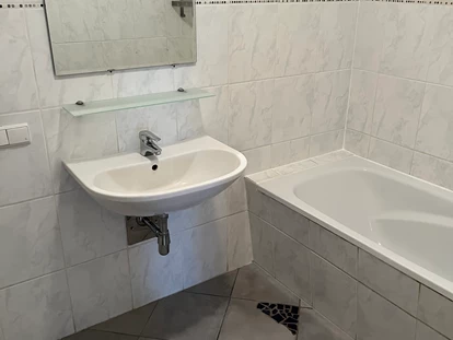 Monteurwohnung - Art der Unterkunft: Apartment - Österreich - Badezimmer mit Waschbecken und Badewanne in der Monteurunterkunft in Dobl-Zwaring. - Azra Sinanovic