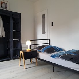 Monteurzimmer: Einzelbett mit Nachttisch - Beata Holz