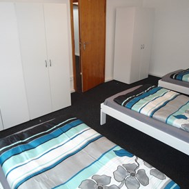 Monteurzimmer: Zimmer 3 mit Einzelbetten und Kleiderschränken in der Monteurunterkunft in Wolfsburg. - BSK-Monteurunterkünfte