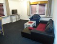 Monteurzimmer: Gemeinschaftraum mit Couch und Fernseher in der Monteurunterkunft in Wolfsburg. - BSK-Monteurunterkünfte