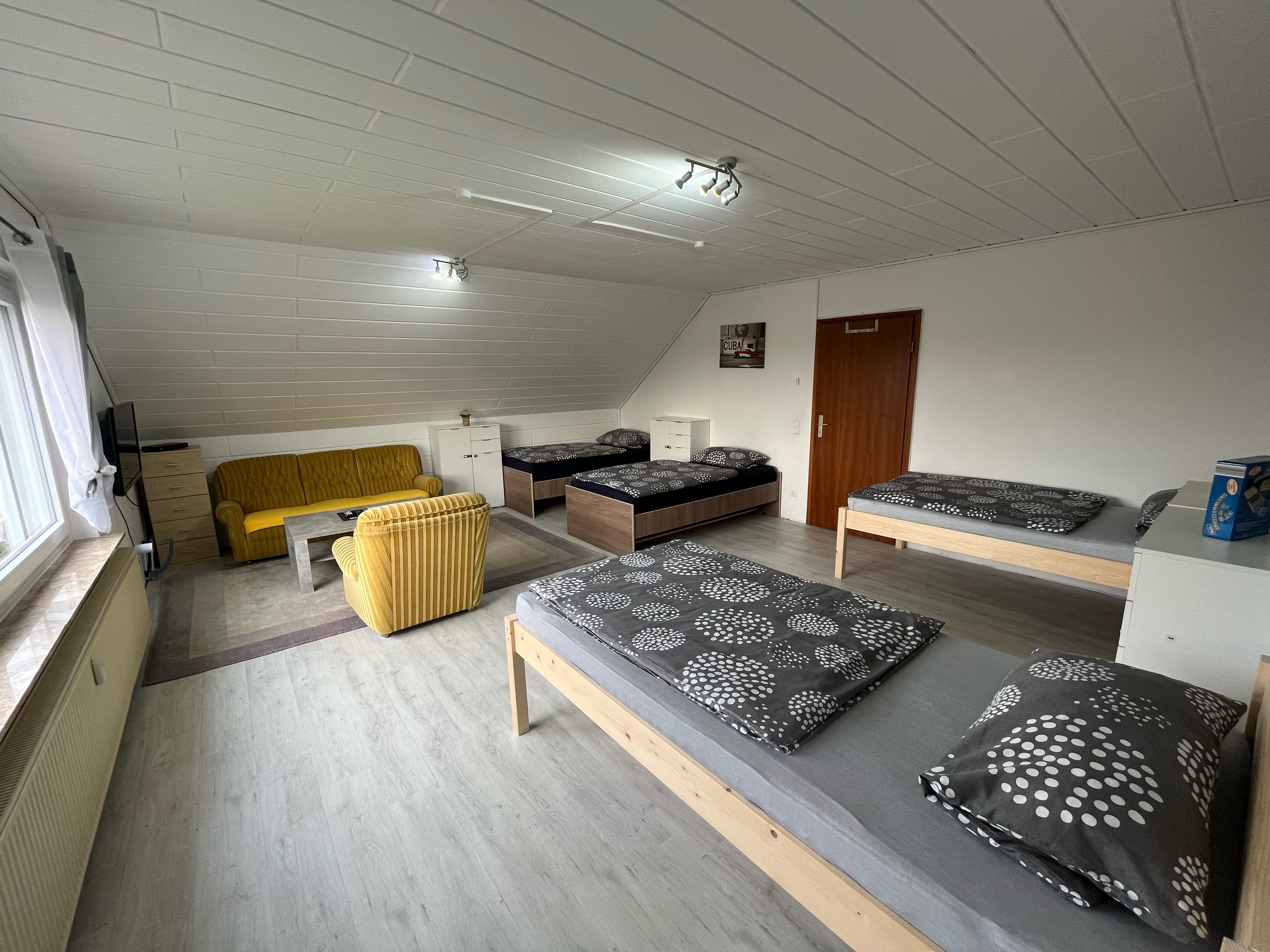 Monteurzimmer: Zimmer 3 / Vierbettzimmer mit 4 Einzelbetten, Couch, Couchtisch und TV. Zu diesem Zimmer gehört ein Wintergarten mit Blick auf den Garten.  - Monteurzimmer Hohenhameln Mehrum 