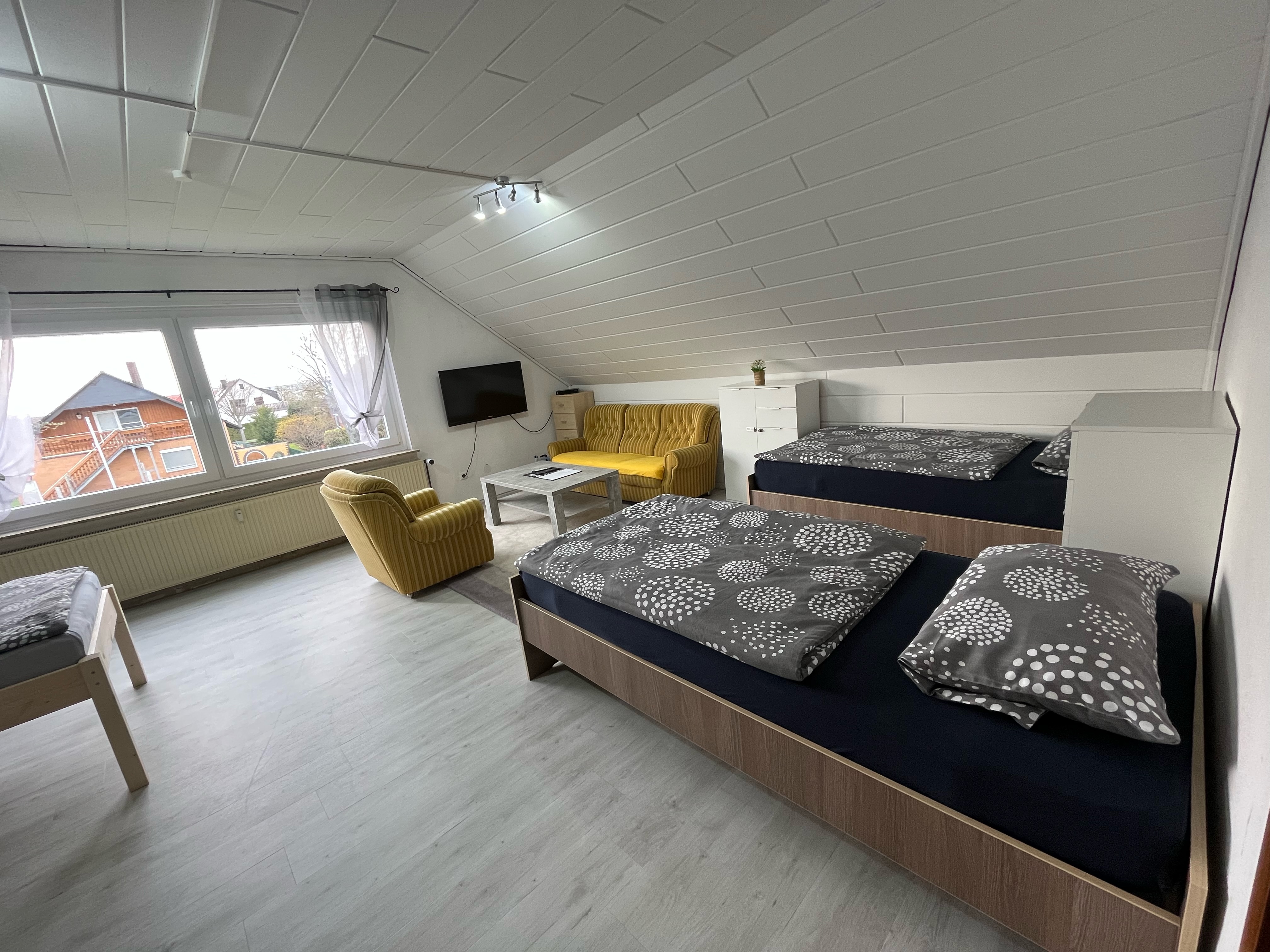 Monteurzimmer: Zimmer 3 / Vierbettzimmer mit 4 Einzelbetten, Couch, Couchtisch und TV. Zu diesem Zimmer gehört ein Wintergarten mit Blick auf den Garten.  - Monteurzimmer Hohenhameln Mehrum 
