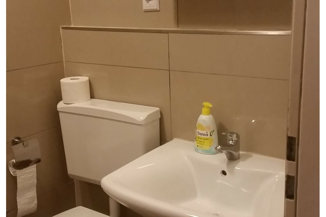 Monteurwohnung: Toilette, Waschbecken und Spiegel im Badezimmer - Monteurwohnung Rastatt