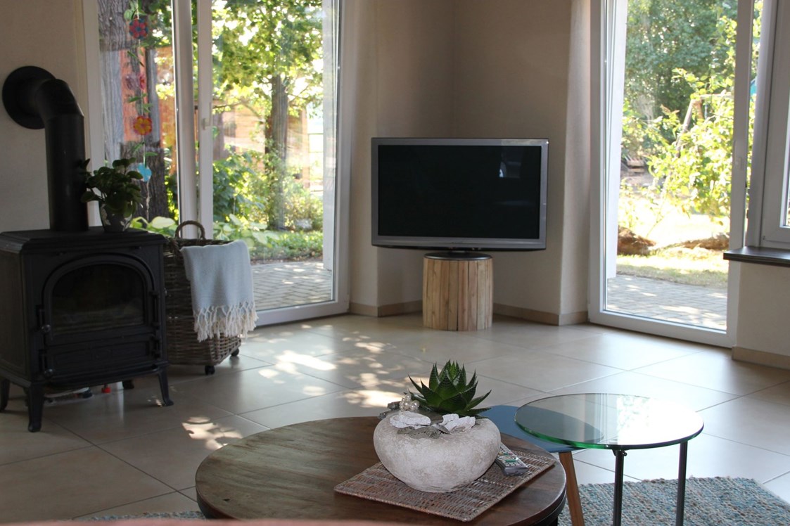Monteurzimmer: Fernseher und Kamin im geräumigen Wohnzimmer mit Blick in den Garten - Ferienhaus "NaturPur"