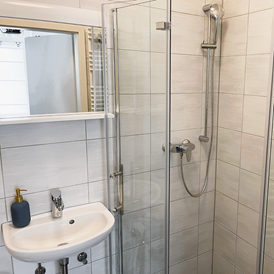 Monteurzimmer: Modernes Badezimmer mit ebenerdiger Dusche, Waschbecken, WC und Waschmaschine. - Apartment Fallersleben 1 in Weimar