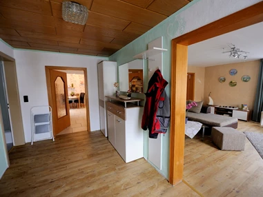 Monteurzimmer: Blick vom Eingangsflur ins Wohnzimmer und Küche,
links Eingangstür Bad - Ferienwohnung Lenk