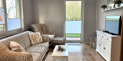 Monteurwohnung - Bettwäsche: Bettwäsche gegen Gebühr - Deutschland - Wohnzimmer mit Couch, Sessel und TV. Zugang zur Terrasse. - ANDY NORDSEE: 2 Schlafzimmerwohnung im Urlaubsparadies