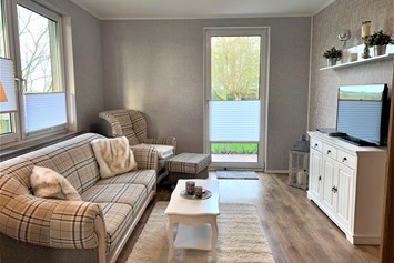 Monteurzimmer: Wohnzimmer mit Couch, Sessel und TV. Zugang zur Terrasse. - ANDY NORDSEE: 2 Schlafzimmerwohnung im Urlaubsparadies