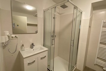 Monteurwohnung: vollausgestattetes Badezimmer mit Föhn und Dusche sowie Waschmaschine - Monteurwohnungen bei Wien