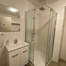 Monteurwohnung: vollausgestattetes Badezimmer mit Föhn und Dusche sowie Waschmaschine - Monteurwohnungen bei Wien