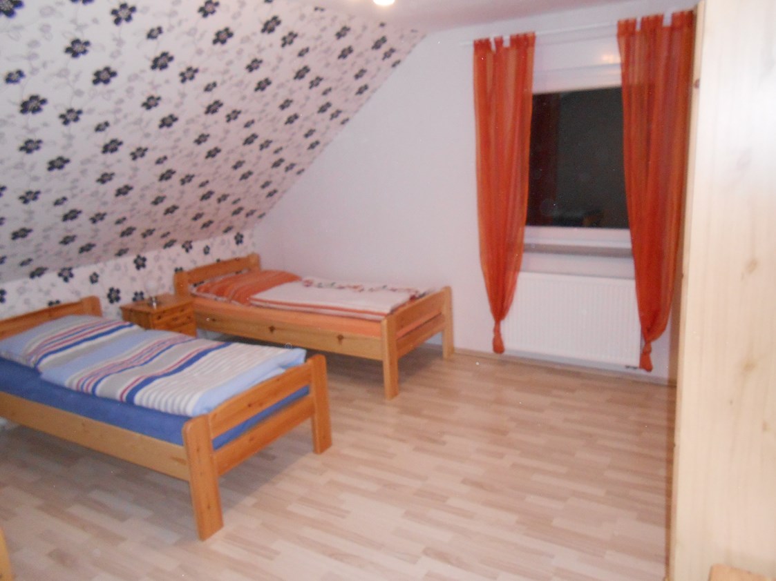 Monteurzimmer: große Schlafzimmer mit Einzelbetten aus Naturholz mit passenden Nachtischen und Kleiderschränken - Gästehaus Böres