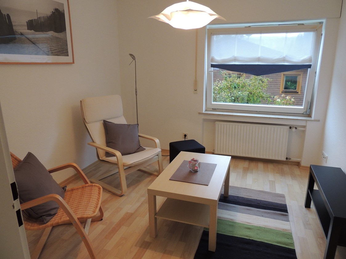 Monteurzimmer: Wohnraum, bestehend aus zwei Sesseln, Couchtisch, Hocker, TV-Schrank mit TV. - Monteur-Apartment