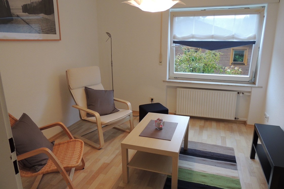 Monteurzimmer: Wohnraum, bestehend aus zwei Sesseln, Couchtisch, Hocker, TV-Schrank mit TV. - Monteur-Apartment