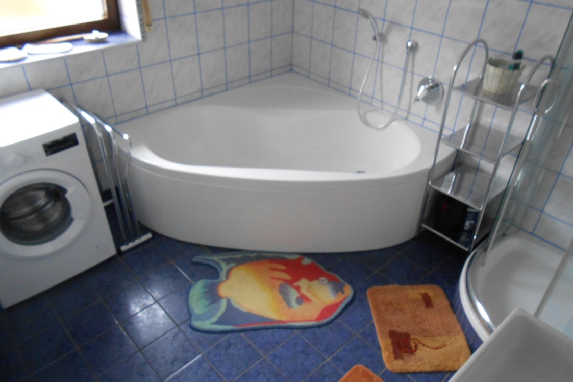 Monteurzimmer: Badezimmer mit Badewanne, Dusche, Waschbecken und Waschmaschine - Gästehaus Lori