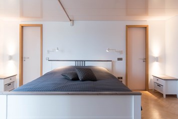 Monteurzimmer: Schlafzimmer mit Doppelbett und begehbarem Kleiderschrank. Zugang zum Hauptbad mit Hauptdusche und Whirlpool. - Lara Loft