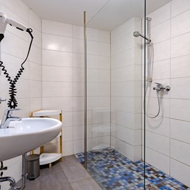 Monteurzimmer: Modernes Gemeinschaftsbad mit großer, ebenerdiger Dusche. - Hostel am Stover Strand
