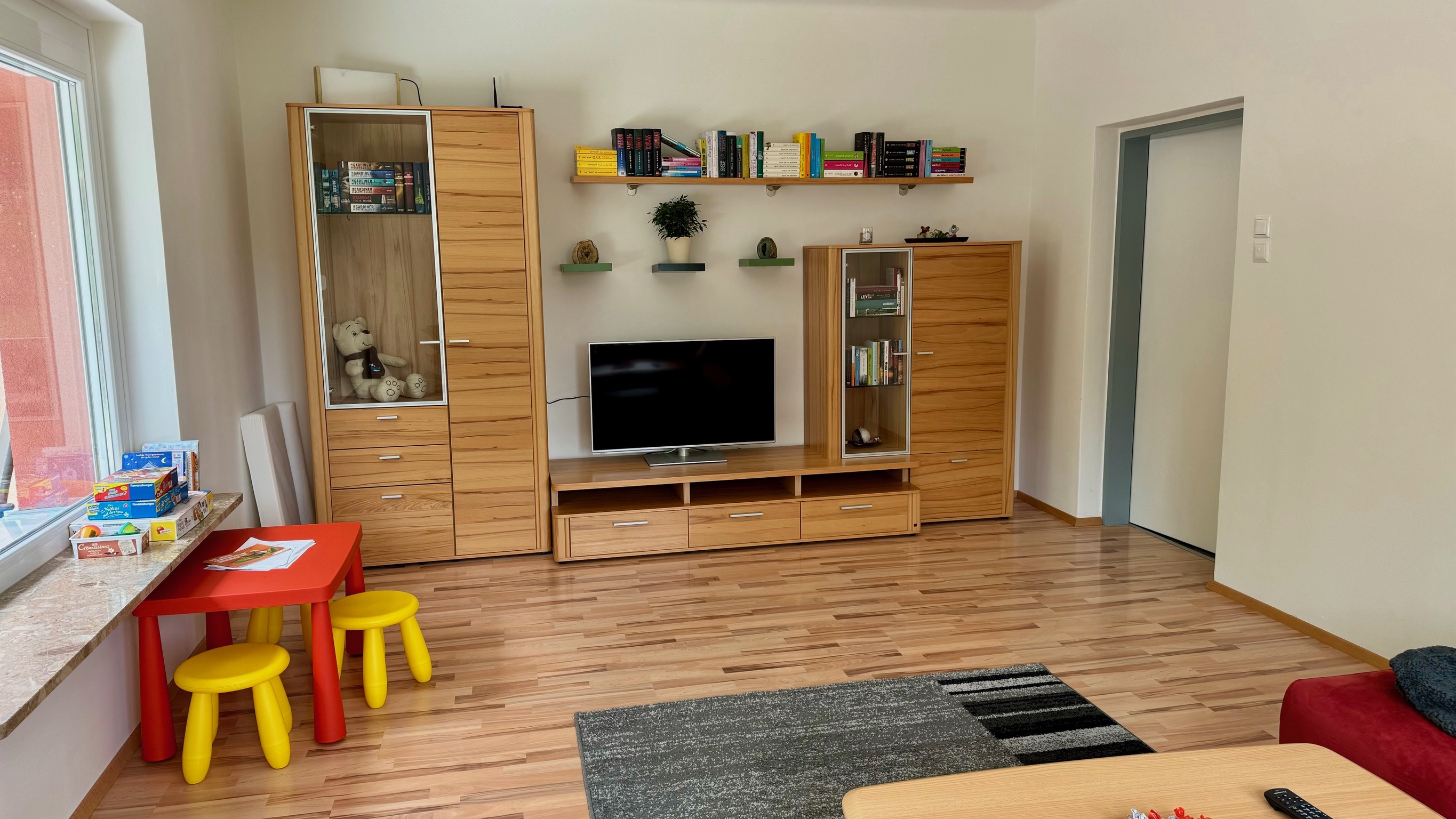 Monteurzimmer: geräumiges Wohnzimmer mit Couch, Tisch, Fernseher und Büchern - Geräumiges Wohnhaus in Wildon, südlich von Graz