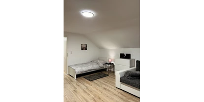 Monteurwohnung - Kaffeemaschine - Schleswig-Holstein - 2. Zimmer mit einem Einzelbett, Esstisch (+ 4 Stühle) einer Schlafcouch und einem TV - Wohnung in dörflicher Lage