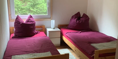 Monteurwohnung - Oschatz - Zweites Schlafzimmer mit zwei Einzelbetten, Nachttisch mit Nachttischlampe, Regal, Stuhl, Fernseher und Verdunklungsrollo. - Pension Lausa