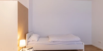 Monteurwohnung - Muggensturm Gaggenau - Einzelbett mit Nachttisch und Kleiderschrank – alles Wichtige ist da.
 - flex living -  Monteurwohnungen in Karlsruhe