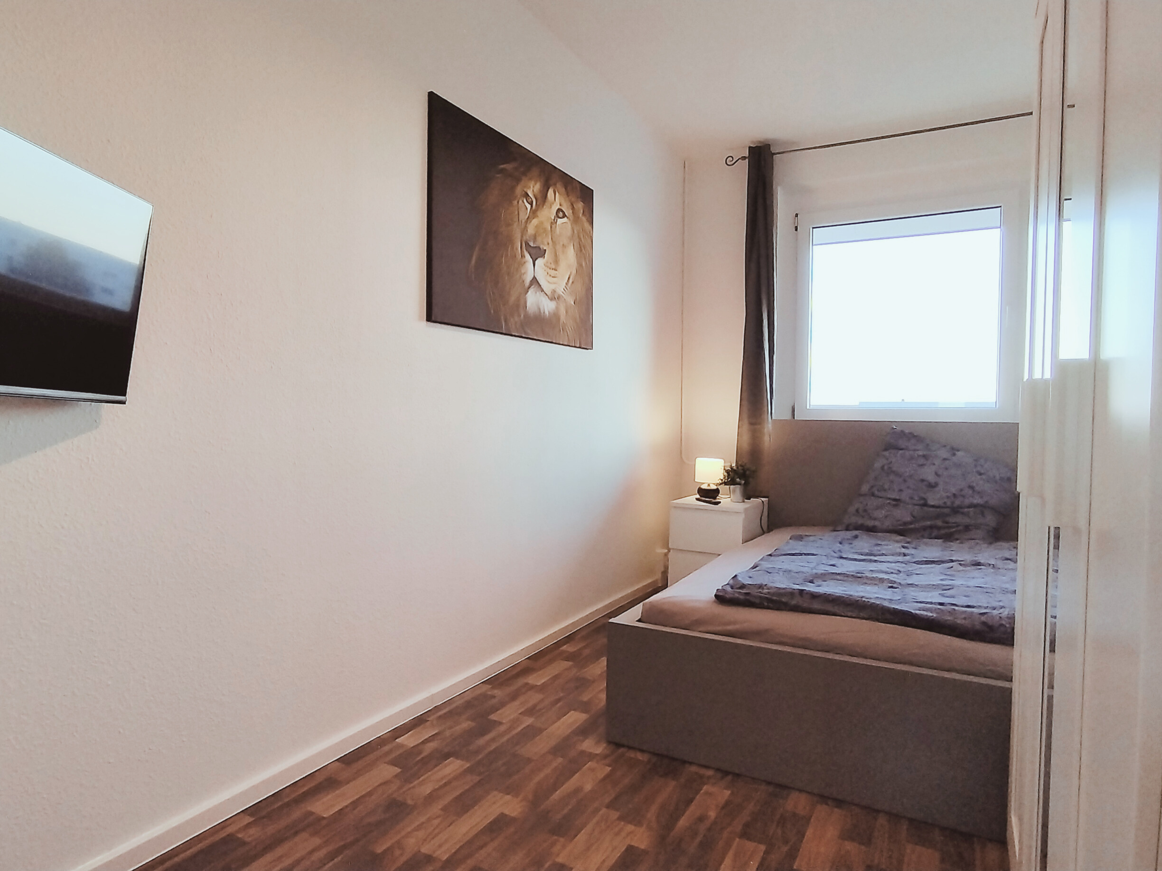 Monteurwohnung - TV - Elbeland - Einzelbett mit Nachttisch und Kleiderschrank – alles Wichtige ist da.

 - flex living -  Monteurwohnungen in Leipzig