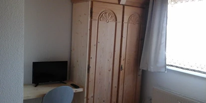 Monteurwohnung - Krautheim (Hohenlohekreis) - Schrank und Tisch mit Stuhl und TV im Doppelzimmer - Haus Johann