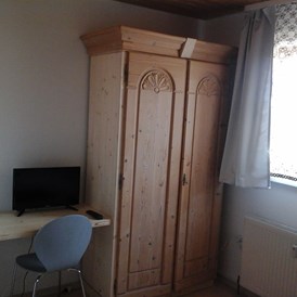 Monteurzimmer: Schrank und Tisch mit Stuhl und TV im Doppelzimmer - Haus Johann