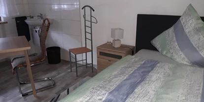 Monteurwohnung - Kronau Walldorf Bretten Kraichtal - Monteurzimmer Philippsburg: Bett, Nachttisch, Tisch, Stühle, Waschbecken - Monteurzimmer