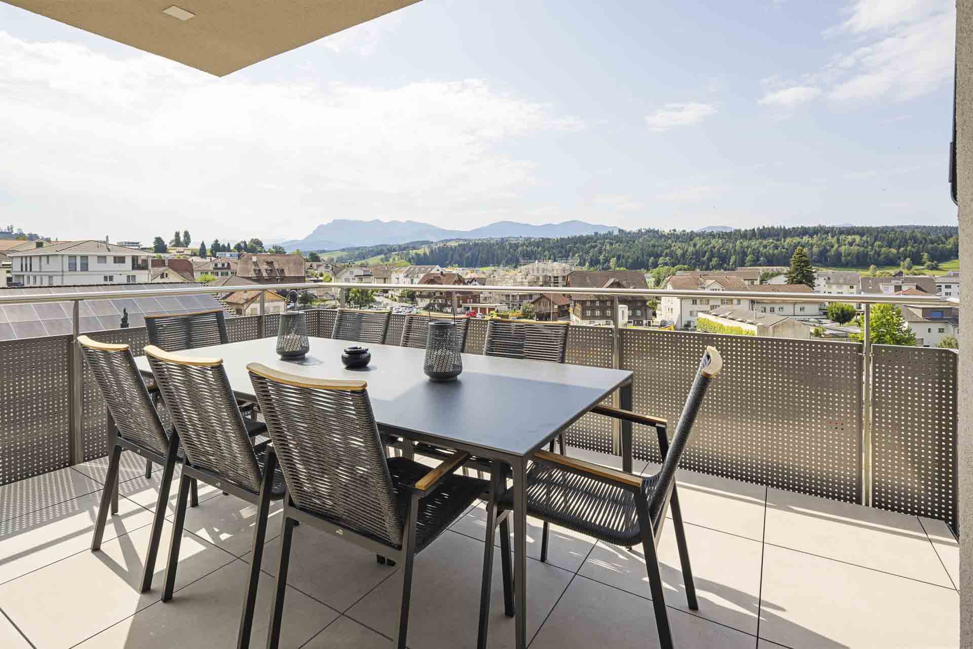 Monteurzimmer: Geniesst gemeinsame Mahlzeiten an der frischen Luft! Ob Familienfrühstück, Team-Lunch oder Stärkung nach dem Sport: Der hochwertige Tisch bietet viel Platz. Die Storen erleichtern euch die Sonneneinstrahlung perfekt zu regulieren.
 - Appartement Pilatus – Perfekte Monteurwohnung