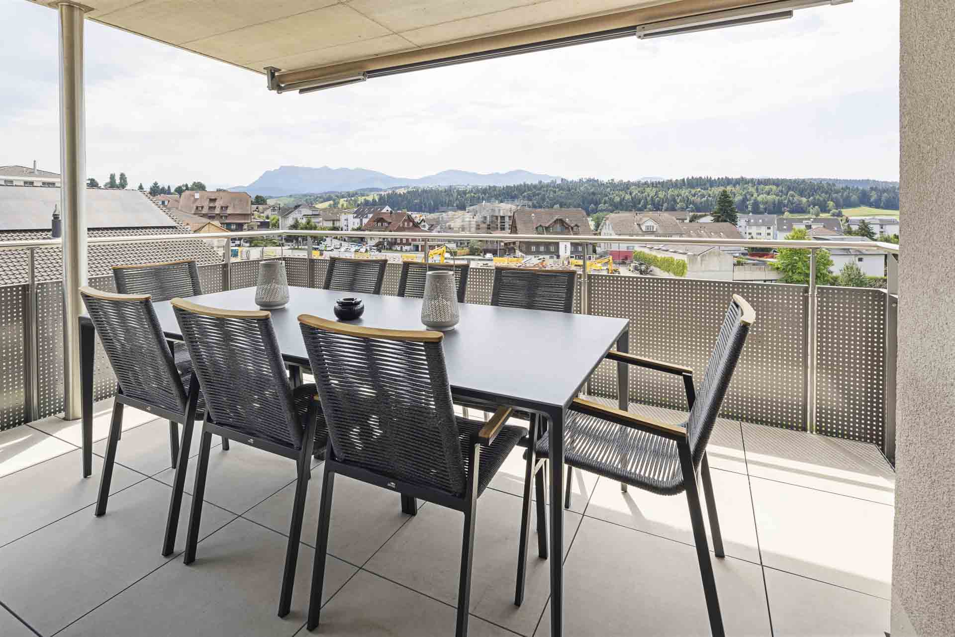 Monteurzimmer: Geniesst gemeinsame Mahlzeiten an der frischen Luft! Ob Familienfrühstück, Team-Lunch oder Stärkung nach dem Sport: Der hochwertige Tisch bietet viel Platz. Die Storen erleichtern euch die Sonneneinstrahlung perfekt zu regulieren.
 - Appartement Rigi – Modernes 2-Zimmer-Appartement im Zentrum