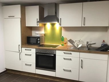 Monteurzimmer: Küche mit Kühlschrank, Backofen, Cerankochfeld und Mikrowelle. - Pfeils Ferienwohnung