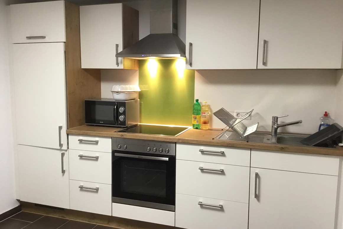 Monteurzimmer: Küche mit Kühlschrank, Backofen, Cerankochfeld und Mikrowelle. - Pfeils Ferienwohnung