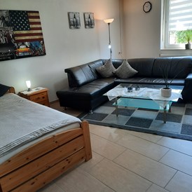 Monteurzimmer: Wohnzimmer mit Ledercouch  TV und zusätzlichen Einzelbett  - Ferienwohnung Marschall Schweinfurt Hassfurt