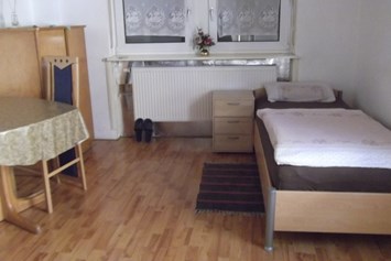 Monteurzimmer: Einzelbett mit Nachttisch - Gästehaus Müller