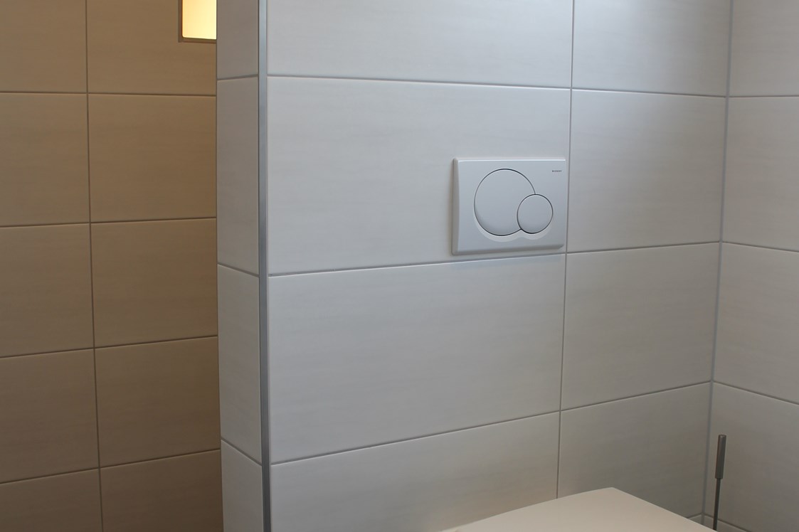 Monteurzimmer: WC, dahinter die Dusche mit beleuchteter Nische zum Abstellen von Pflegemitteln, Seife, Duschgel usw, - Monty